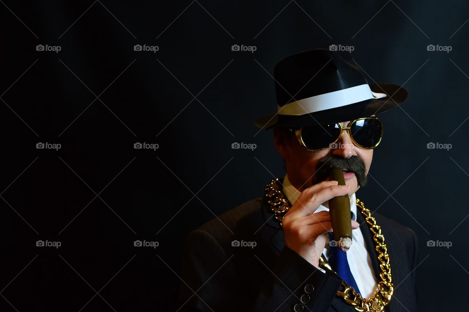 Man in suit wearing gold chain smoking cigar