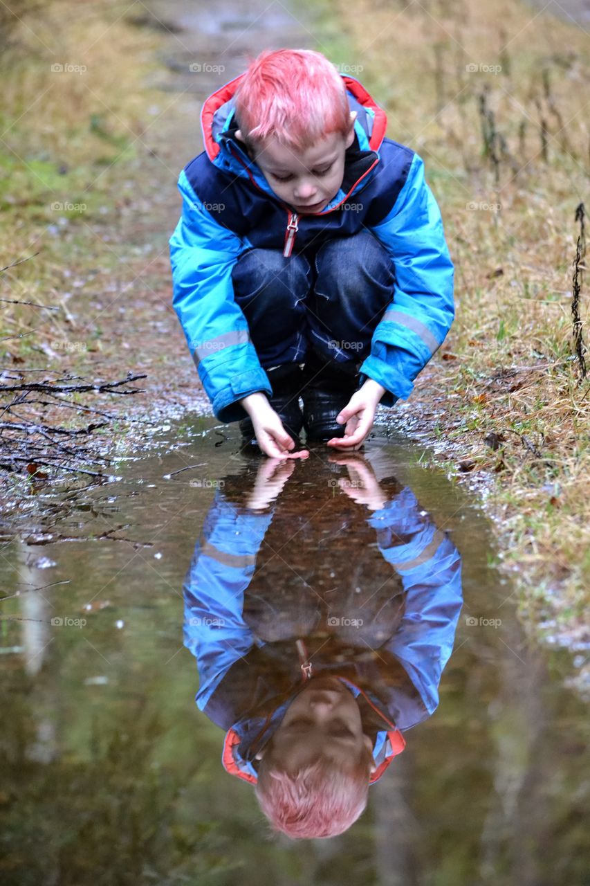 Boy's reflection in puddle