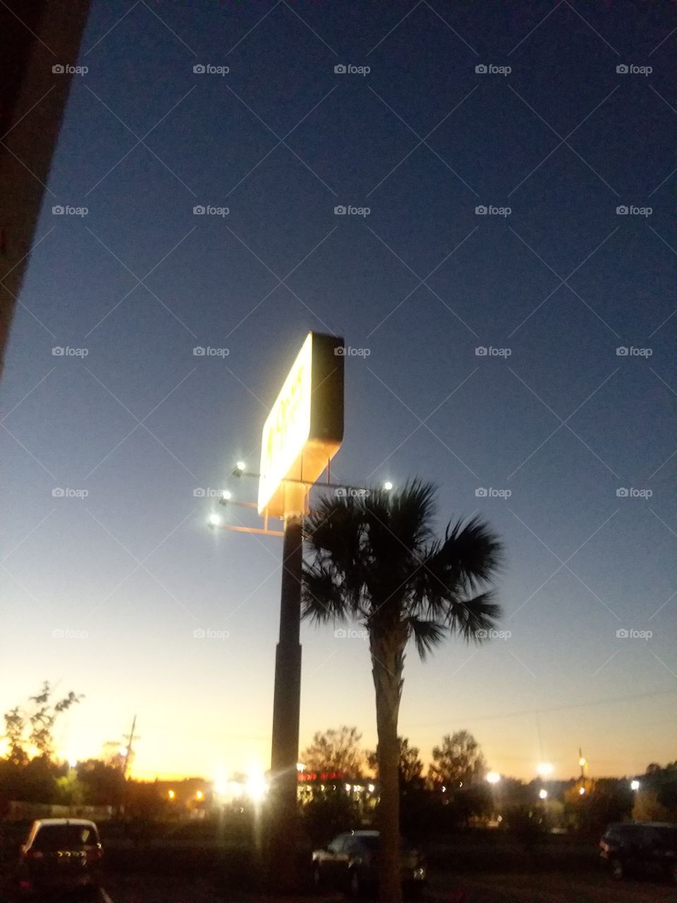 natural light vs artificial light  sign lit up at dusk with the last of sunlight along the horizon