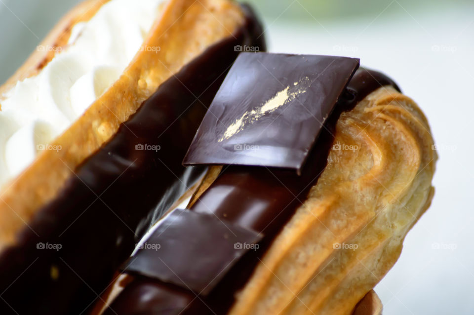Dark Chocolate closeup square shaped on eclair puff pastry with cream
