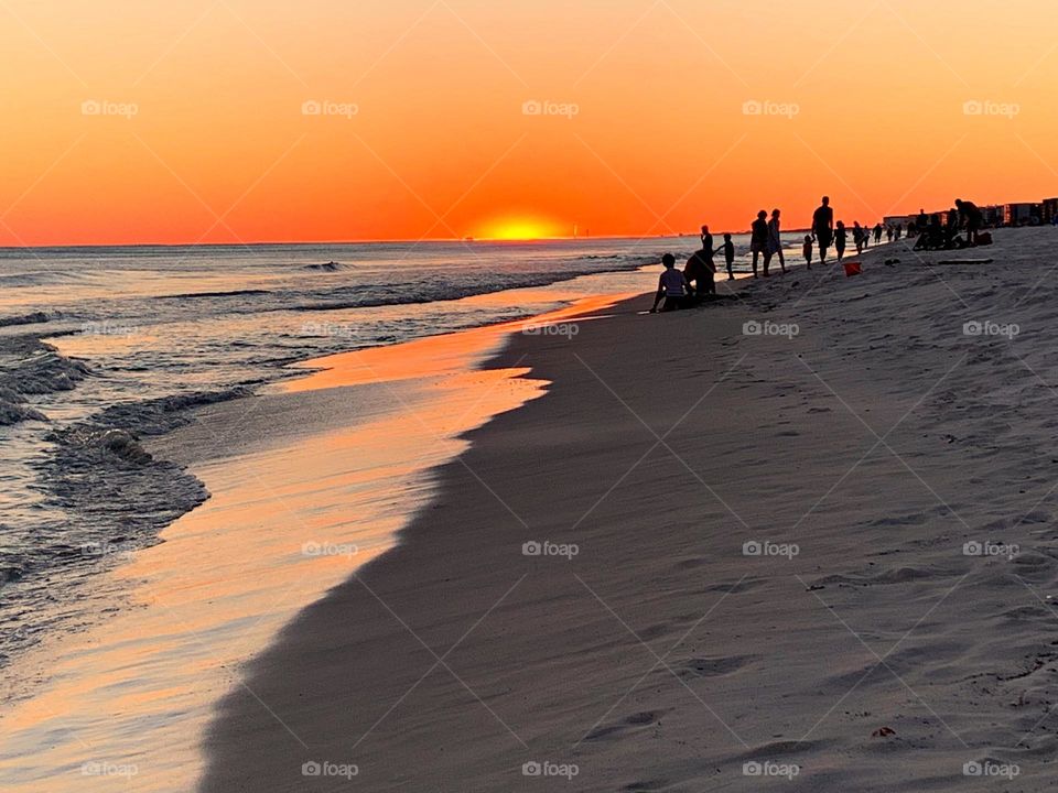 The big orange and crimson ball slowly going down and down and it sets into the horizon making the sky absolutely stunning It was sunset. I watched with an unwavering gaze, as a fiery orange orb of light slowly sank beneath the horizon