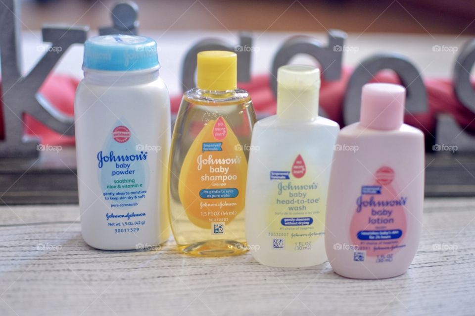 Johnson and Johnson baby products on a white rustic background with the word kisses in the back in a pink towel
