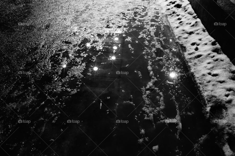 Constellation of slush. Reflection of lights appear as constellation in wet slush
