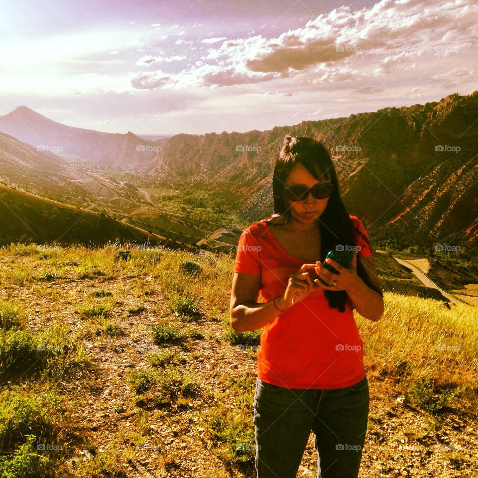Woman standing in front of mountain range using mobile