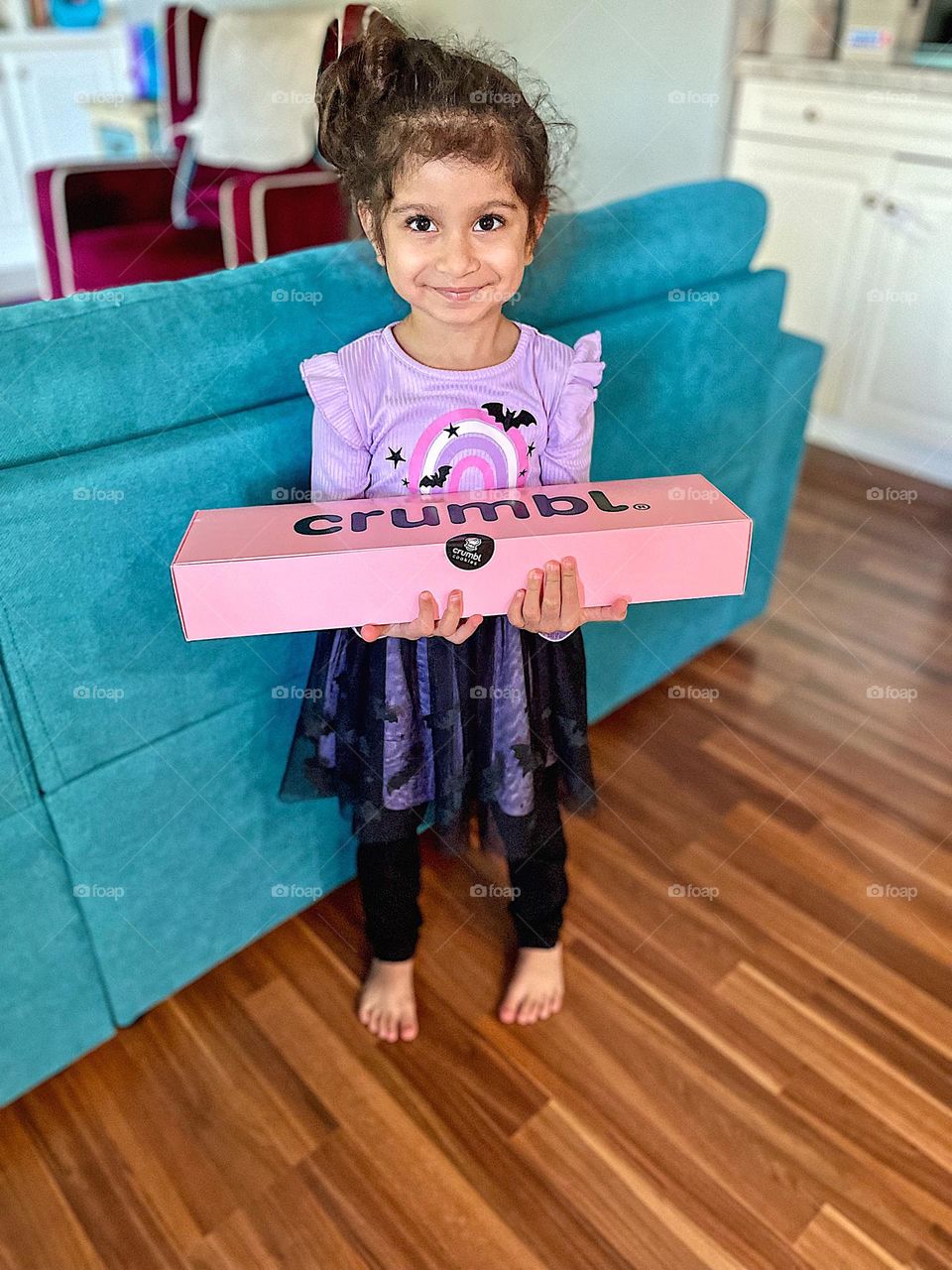 Little girl holds box of Crumbl cookies, celebrating birthdays in the fall, celebrating with cookies, Crumbl cookie advertising 