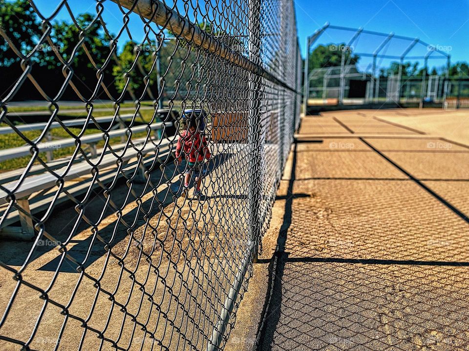Little girl walks behind dug out, toddlers and baseball, toddler girl on a baseball field, Americas past time, sports and children, exploring baseball fields with toddlers