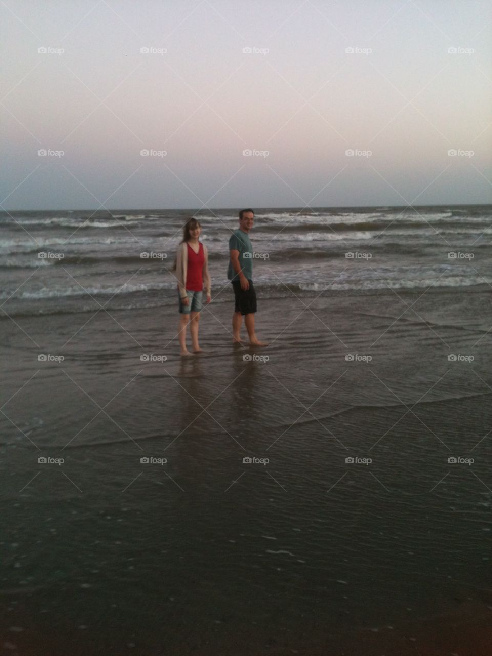 Father and daughter stroll along the beach