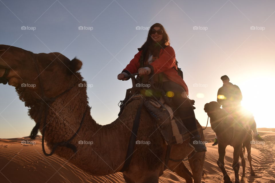 Couple riding arabian camels at Sahara desert, Morroco