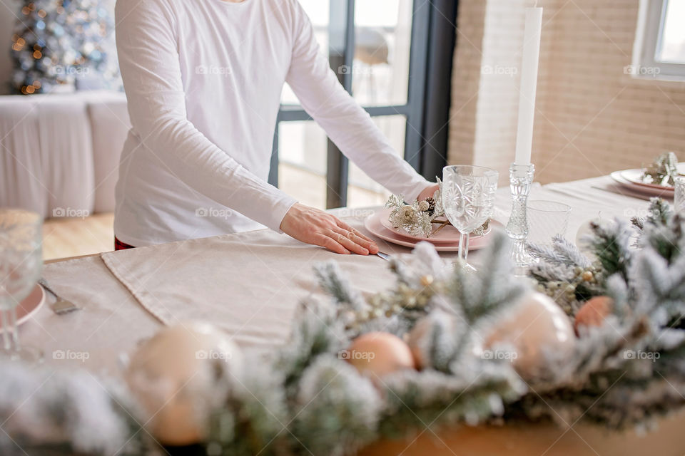 man sets a beautiful decorated winter table for a festive dinner.  Merry Christmas and Happy New Year.