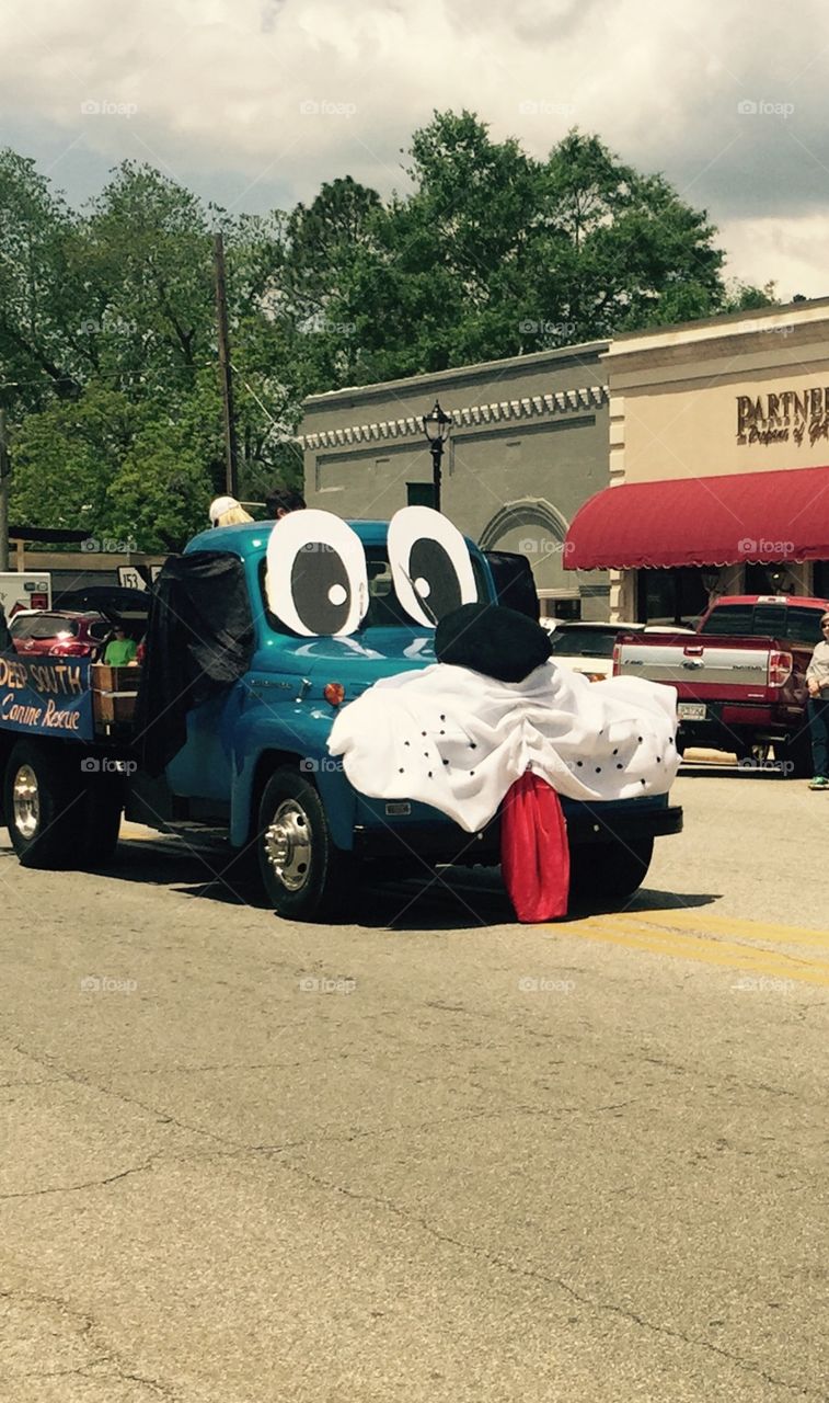 A big dog float with big black eyes and red tongue hanging out as it travels in the parade to promote adopting a dog.