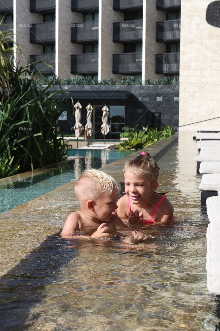 Cute blonde siblings having fun at the pool on a  cancun vacation 