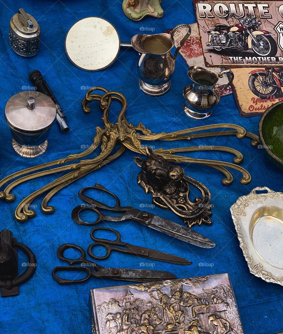 Vintage flea market in Poland with unique decorations, old brass hangers, silver plate on the bright blue background 