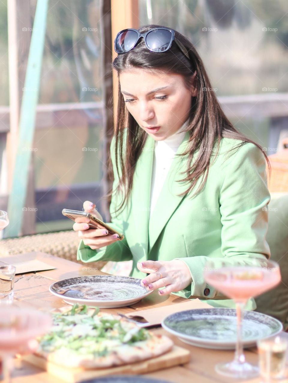 One handsome Caucasian brunette girl with long flowing hair in a mint business suit with great surprise on her face stands at the table in a street kaye looking at an empty plate, side view close-up. Surprised people concept.