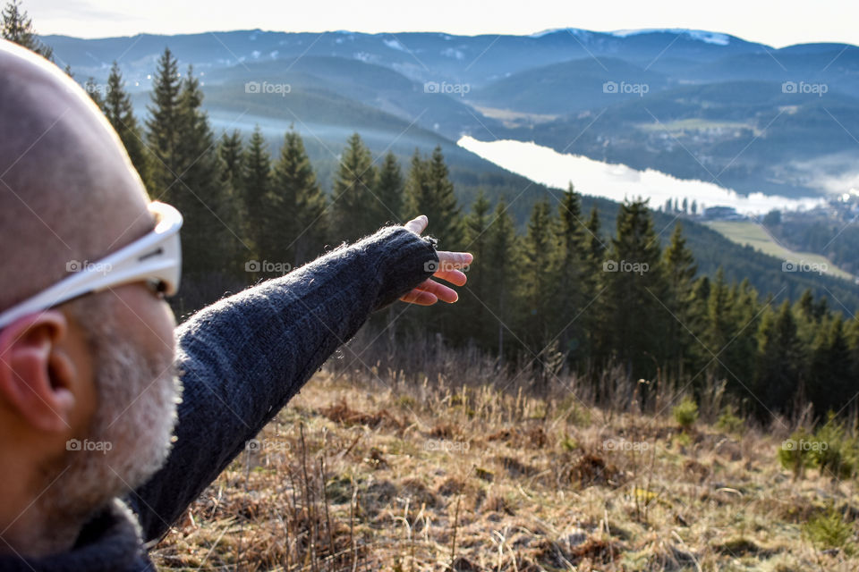 a man shows the lake and enjoys the view in the mountains