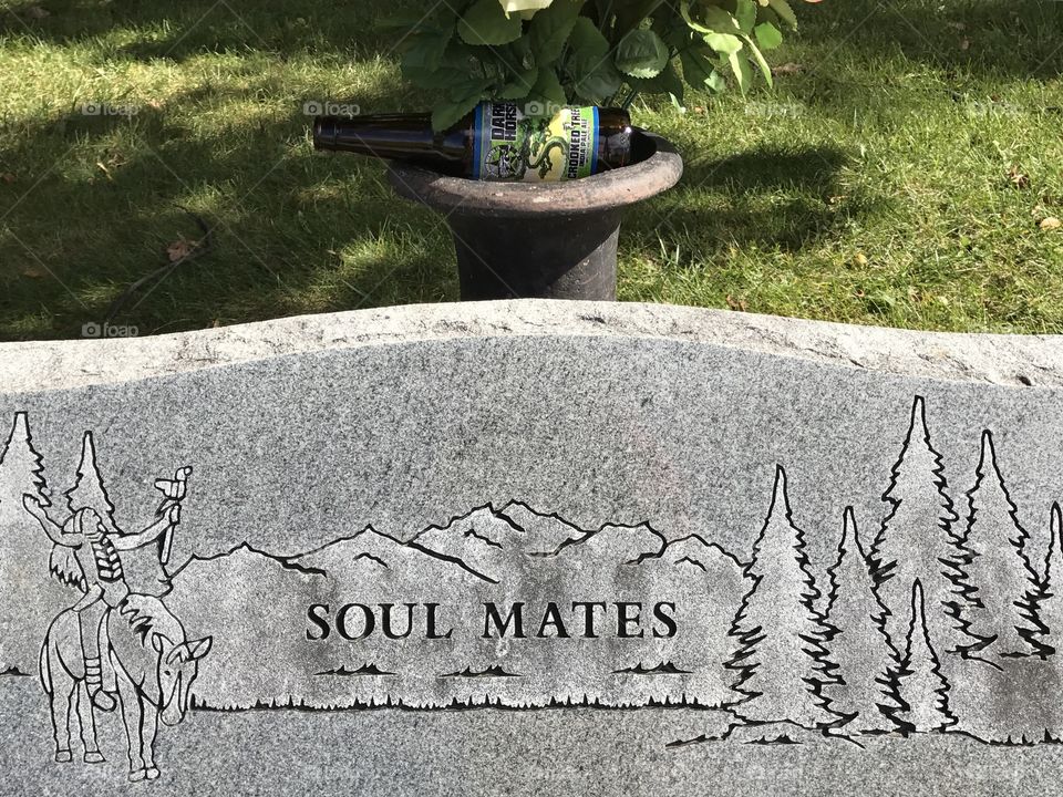 A soulmates inscription on a gravestone and behind it someone littered.