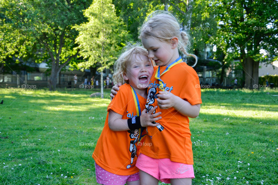 Two young sisters is hugging after they finished a running race together in Stadsparken Lund in Sweden.