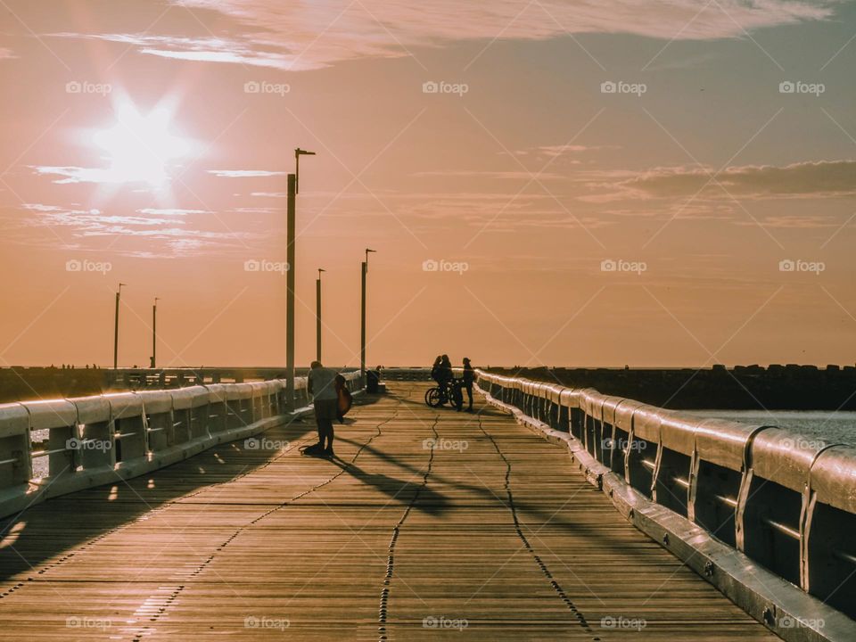 Beautiful sunset view of the deoevyan pier with blurry people in the distance in the north sea in the city of Oostende in belgium, close-up side view.