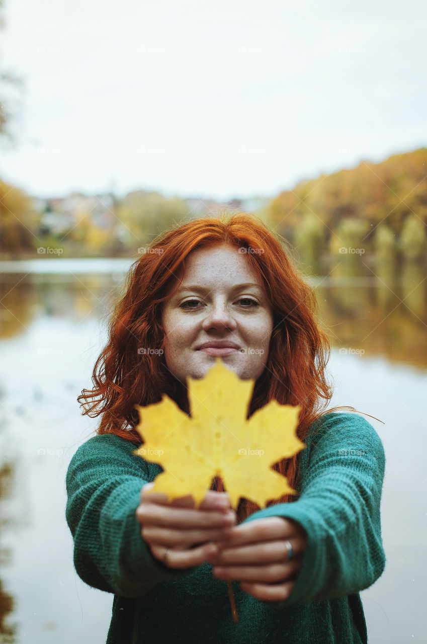 Redhead funny girl with yellow leaf enjoy in autumn park.