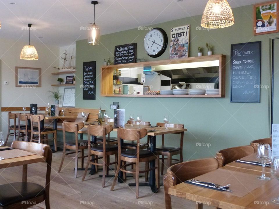 This café-pizzeria is decorated in a sober and warm style both in natural tones, natural green color and wood material. The opening onto the kitchens creates a link between the restaurateur and his customers.