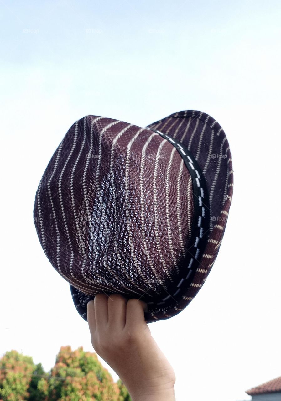 Hat in a hand against the clear sky