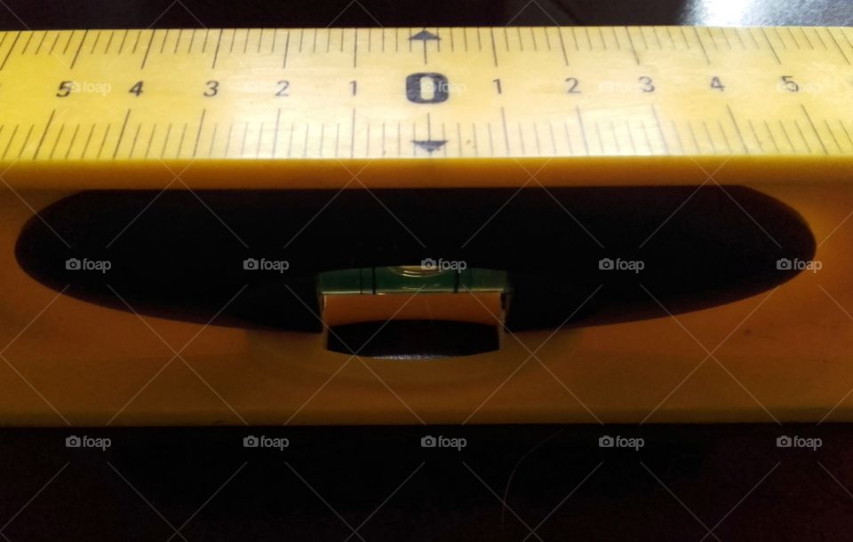 Yellow and black spirit level with numbered measurements on top edge