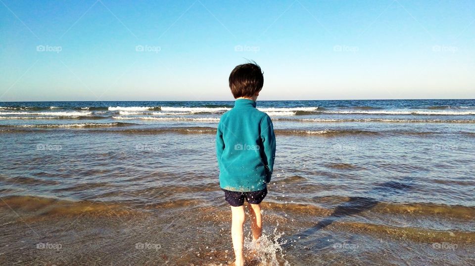 one boy playing with water in the sea