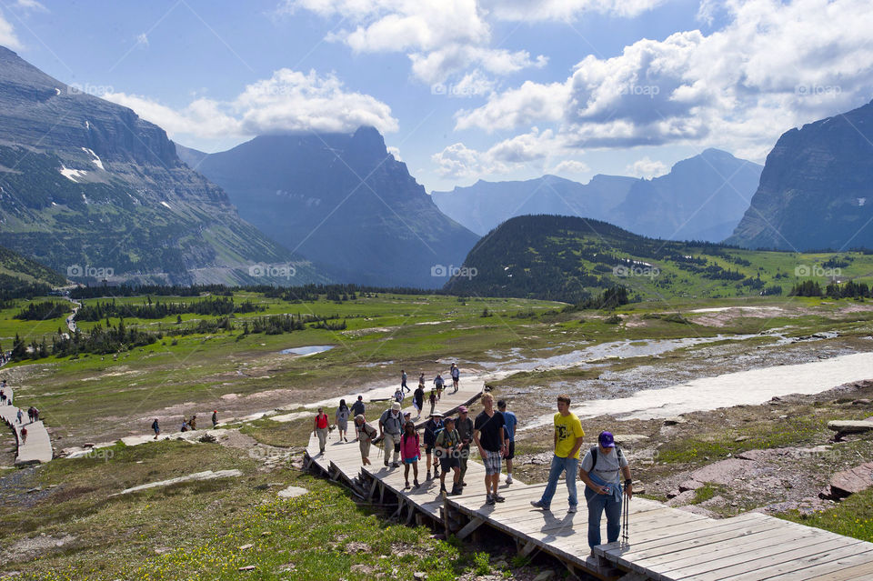 Visitors to Glacier National Park hike on a wood-planked trail.