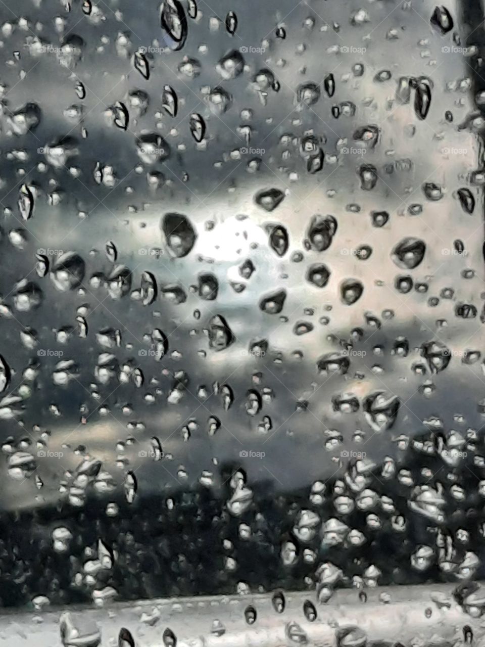 raindrops on car mirror and reflection  of sky