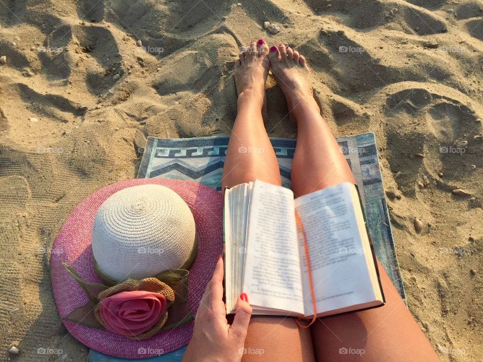 Woman reading on the beach with summer hat near