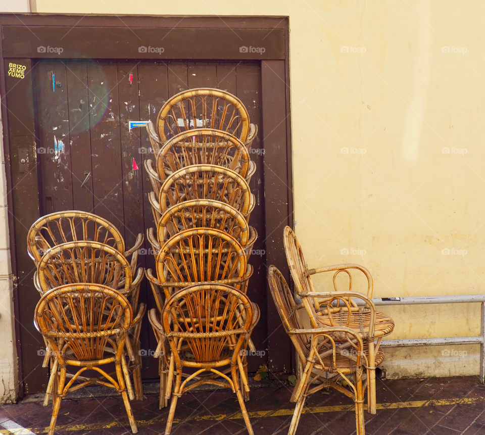 Cafe chairs piled up against yellow and brown wall on the Cours Saleya in Nice, France.