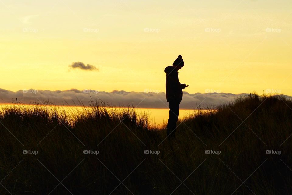 Sunset on Holy Island … silhouette of my son trying to get a signal in his phone 