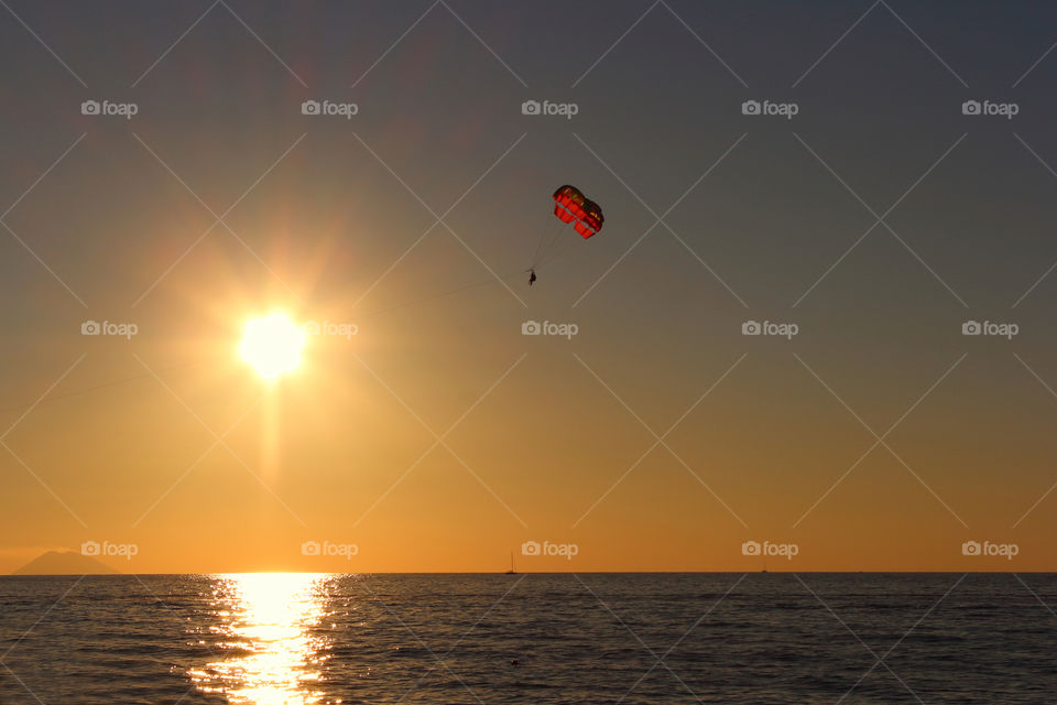 Person paragliding during sunset over the sea