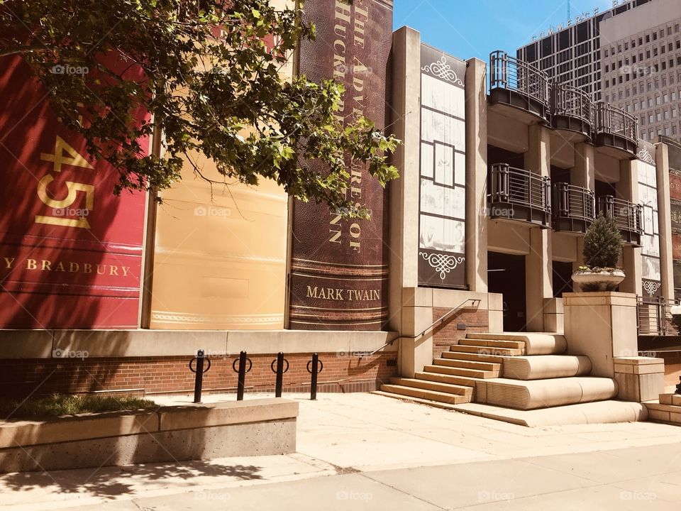 Gorgeous wall mural on library in Kansas City, MO of books lined up and the building is even complete with books stacked on each other for steps!! 