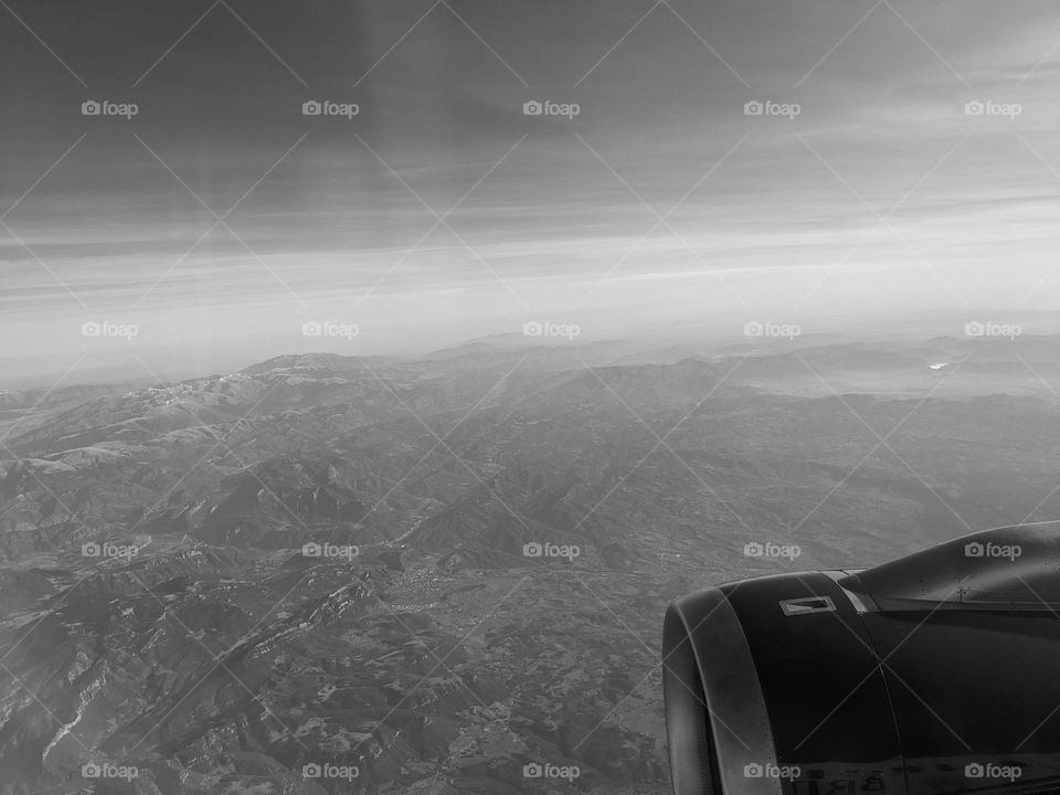 Looking out the airplane window. Part of the plane is visible in the lower right corner. A mountain landscape, the horizon is low.