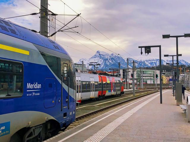 Salzburg, Austria. Train Station with snow covered Alps Mountains in background. Travel by train, Winter holiday, Vacation, Europe tourism, Ski resorts.