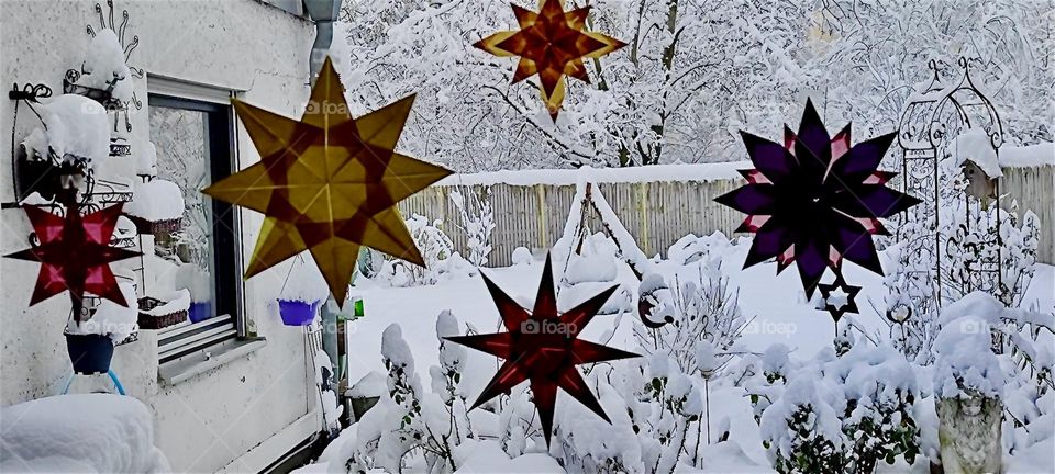 Through a large window adorned with folded stars made from metallic foil just in time for Christmas we see the snow covered garden of the beautiful house in „Bavaria“, Germany that we have visited before. 2023. Hypnotic Productions