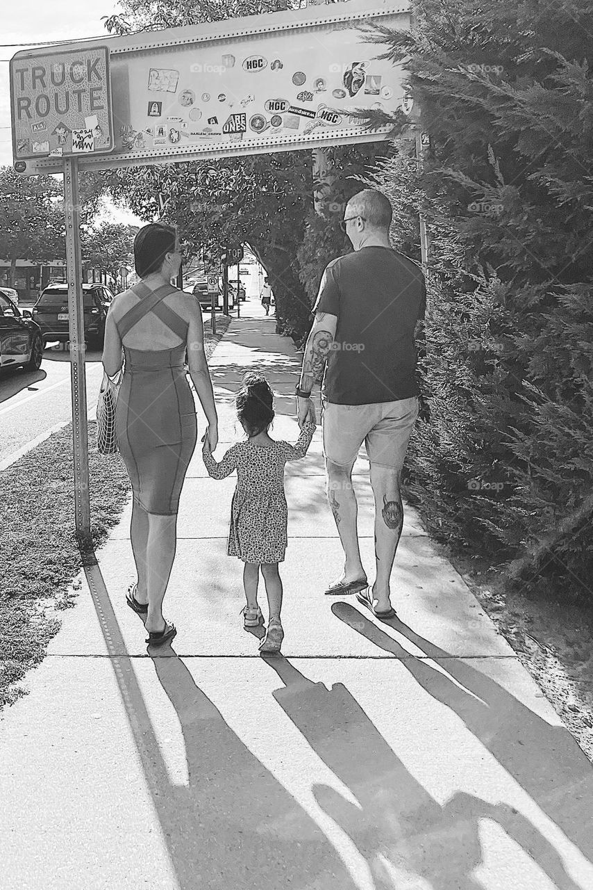 Family walking on sidewalk, black and white family image, black and white walking family portrait, holding hands as a family