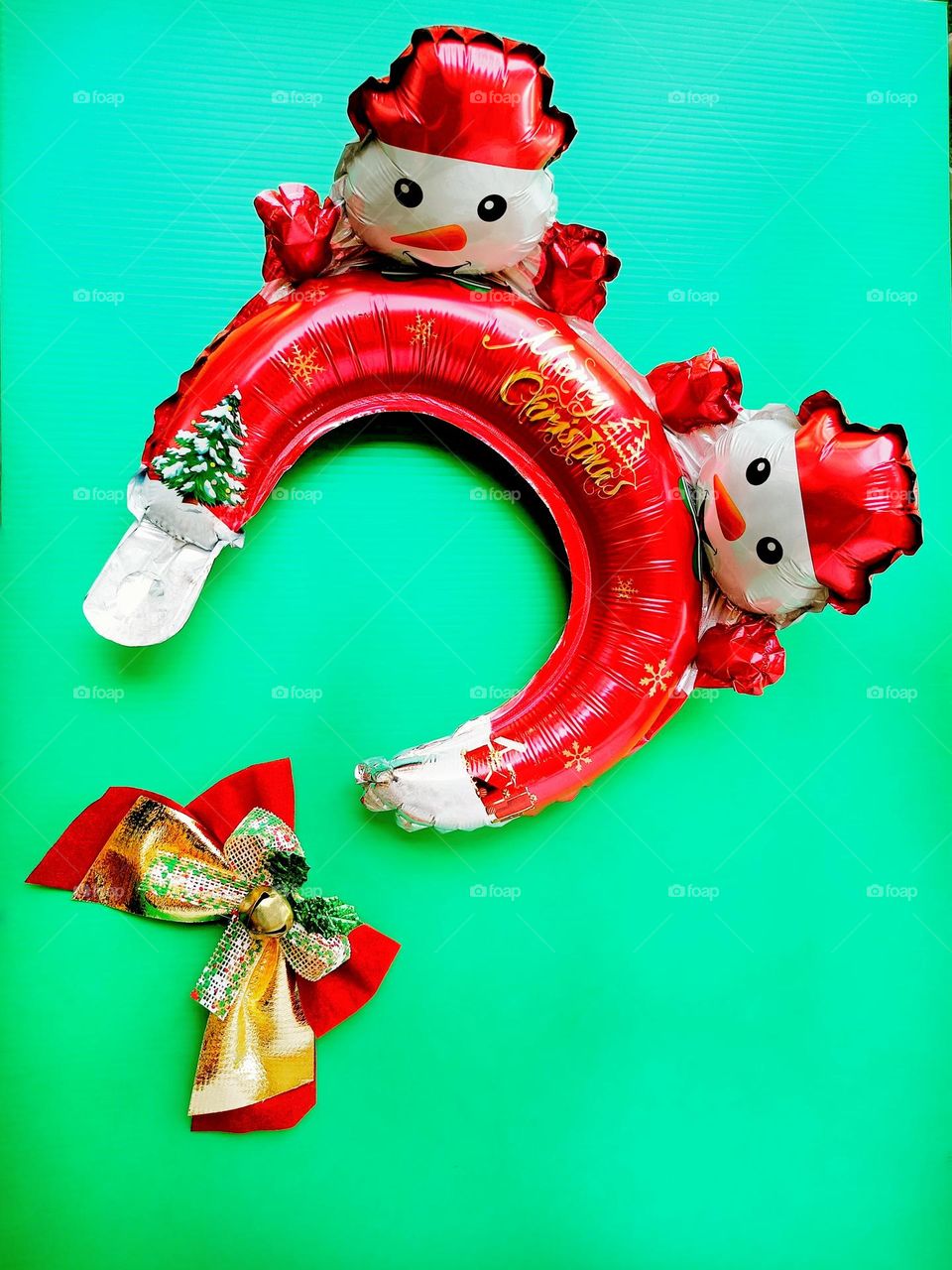 Snowman Christmas headband and Christmas bow on green background vertical composition.Christmas balloons headband, Christmas foil balloons or Inflatable headband.Christmas accessories.