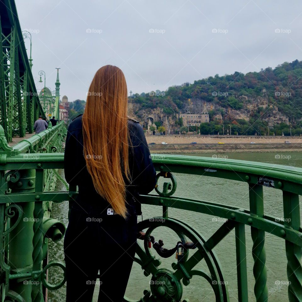 yling girl with blonde hair looking from the bridge over the Danube in Budapest