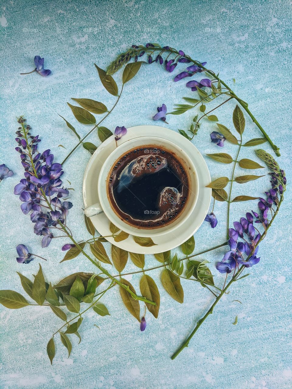 Background of a cup of hot coffee on the table with beautiful flowers close-up. Top view.