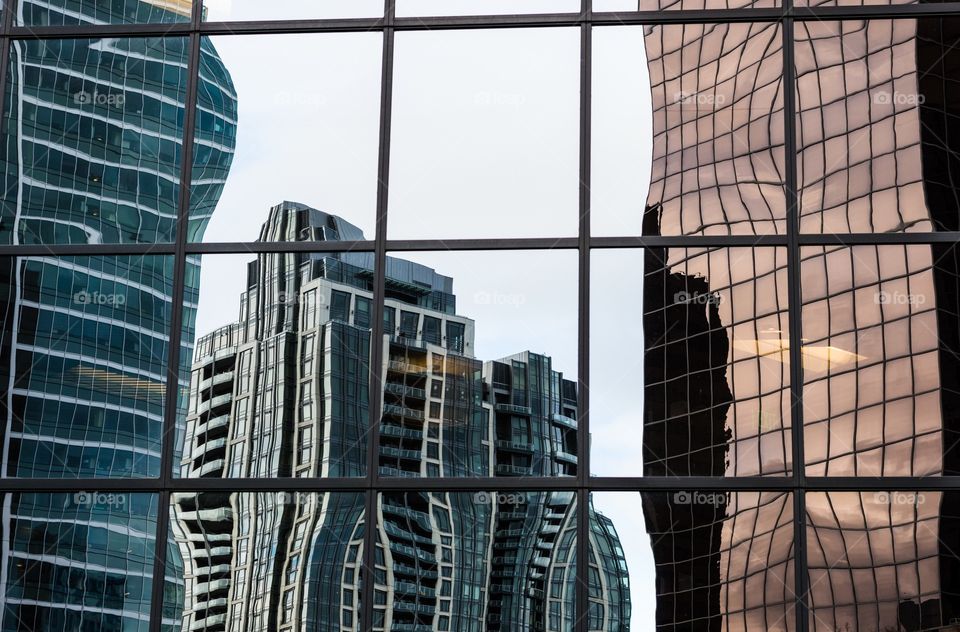 Warped reflections . Warped reflections of modern glass buildings  in another glass building downtown .