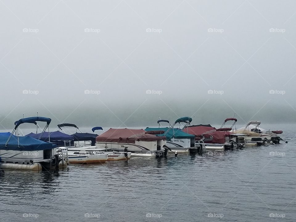 fishing boats with colorful covers docked on foggy morning