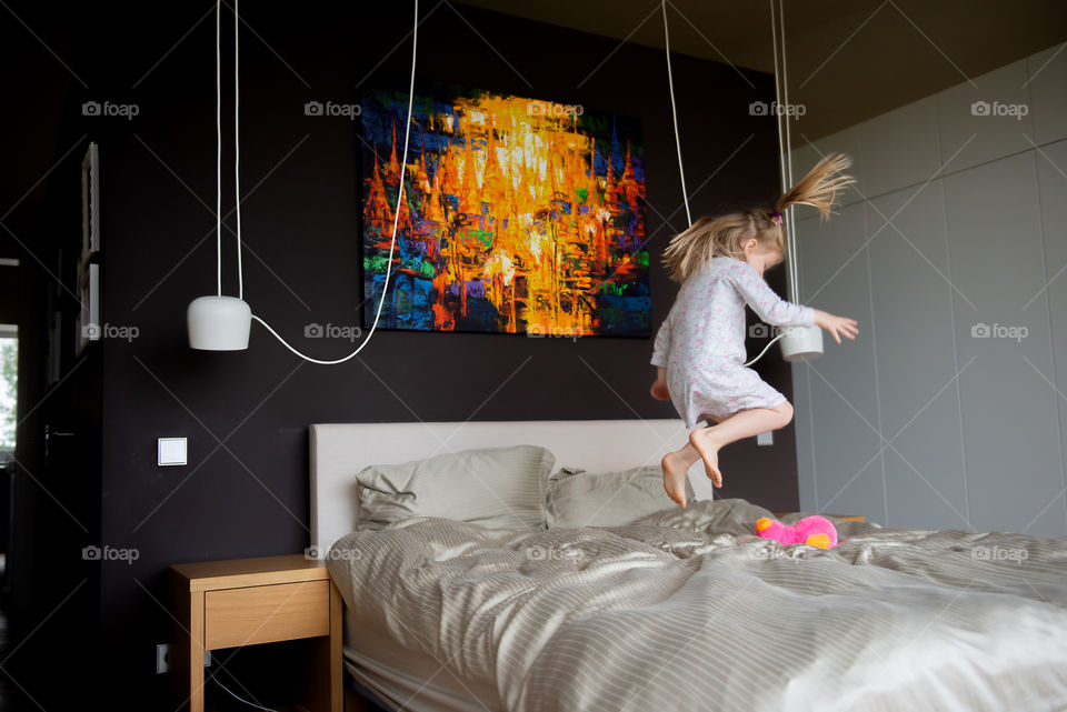 Little girl jumps on the bed
