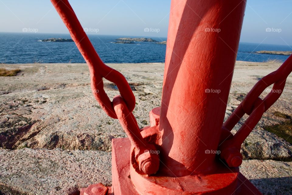 Red metallic pole on rock