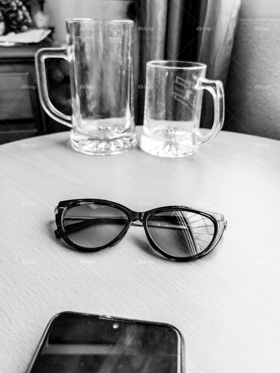 Phone, sunglasses, beer mugs still life