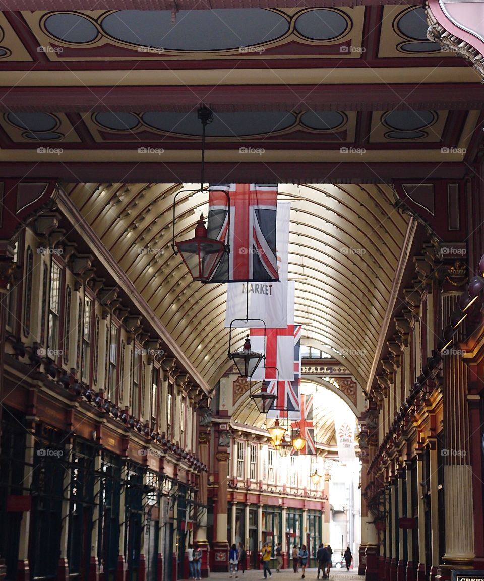 British and Market flags on the ceiling of a stylistic outdoor building in London, England on a summer day. 
