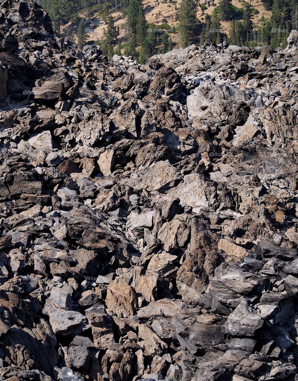 A great mass of hardened lava at the Big Obsidian Flow in Newberry National Volcanic Monument in Central Oregon on a sunny fall day. 
