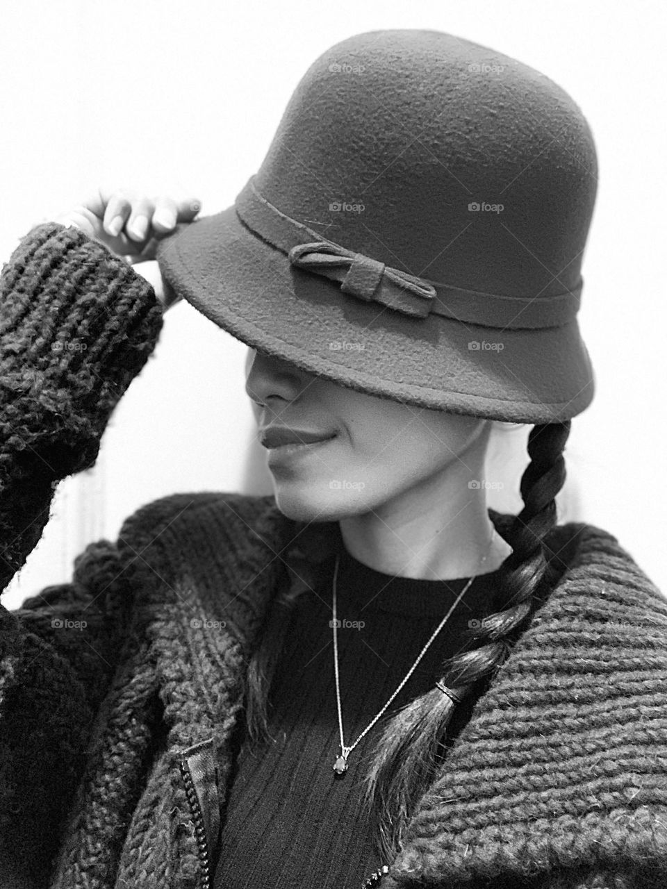 A woman holding her hat. Black and white.