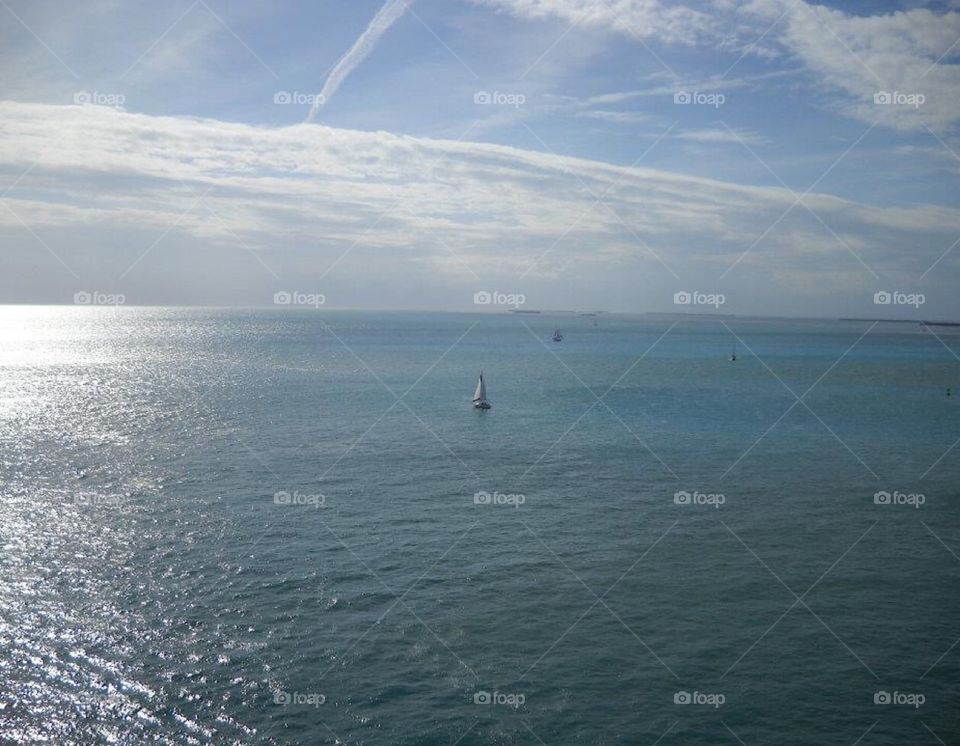 Bright blue ocean with small sail boats in the distance