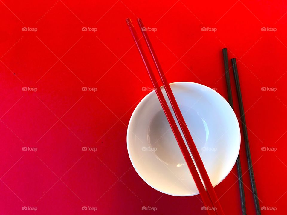 White bowl with chopsticks on red
